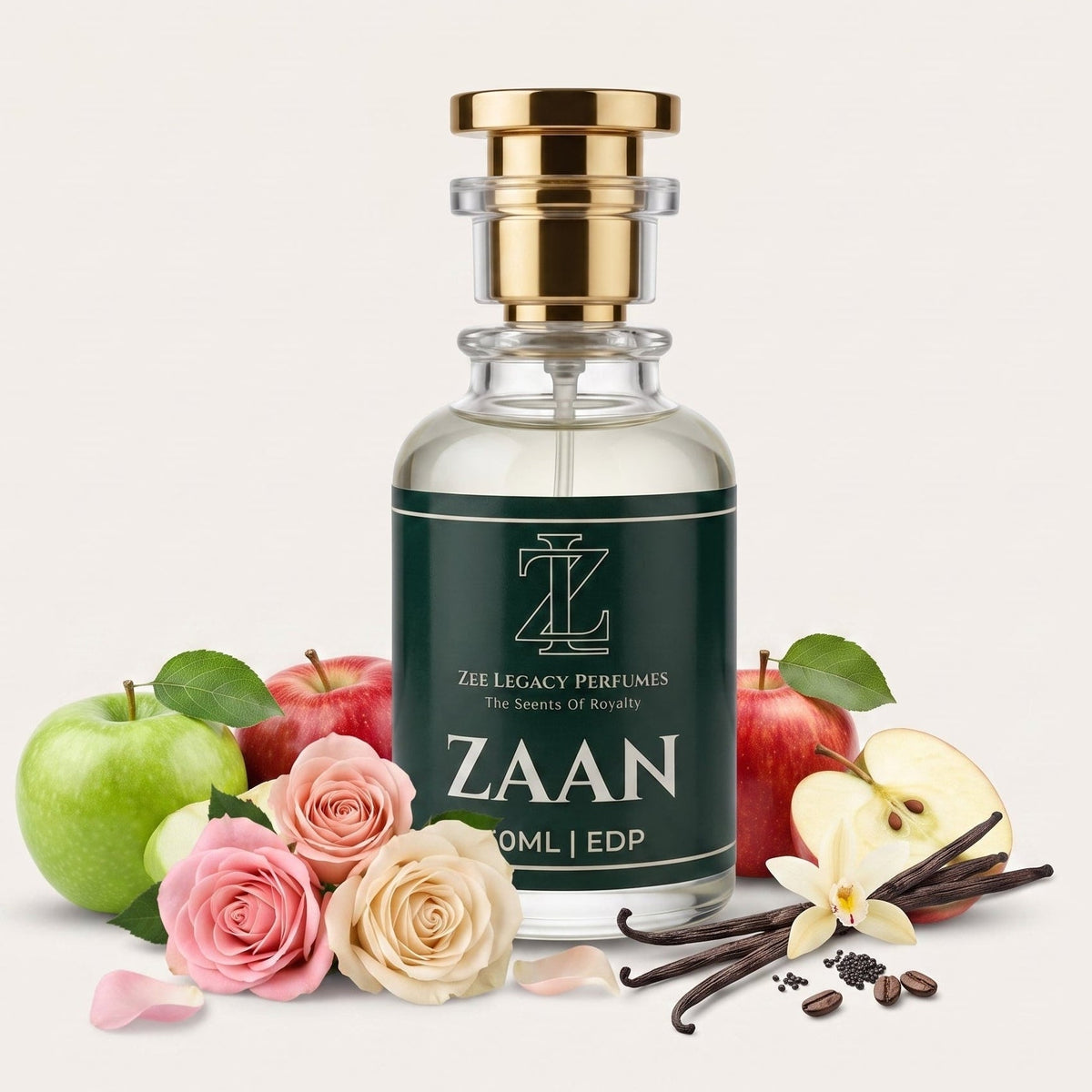 A clear glass perfume bottle with a dark green label reading 'ZAAN' and 'ZEE LEGACY PERFUMES', topped with a gold cap. The bottle is styled with red apples, pink and cream roses, vanilla beans, and flower petals on a light beige background.